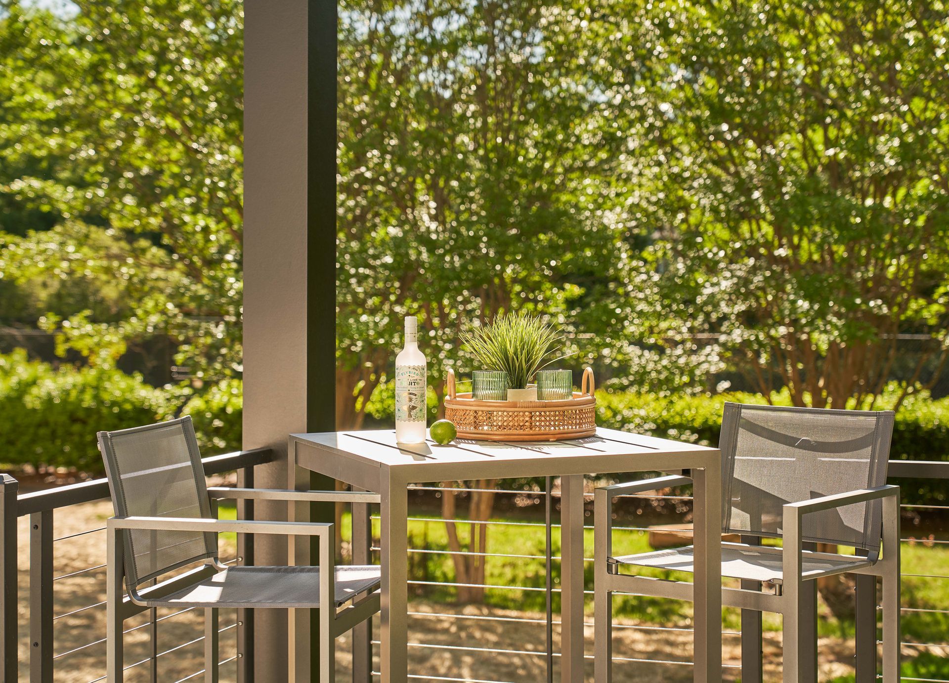 A patio with a table and chairs and a bottle of wine on it.