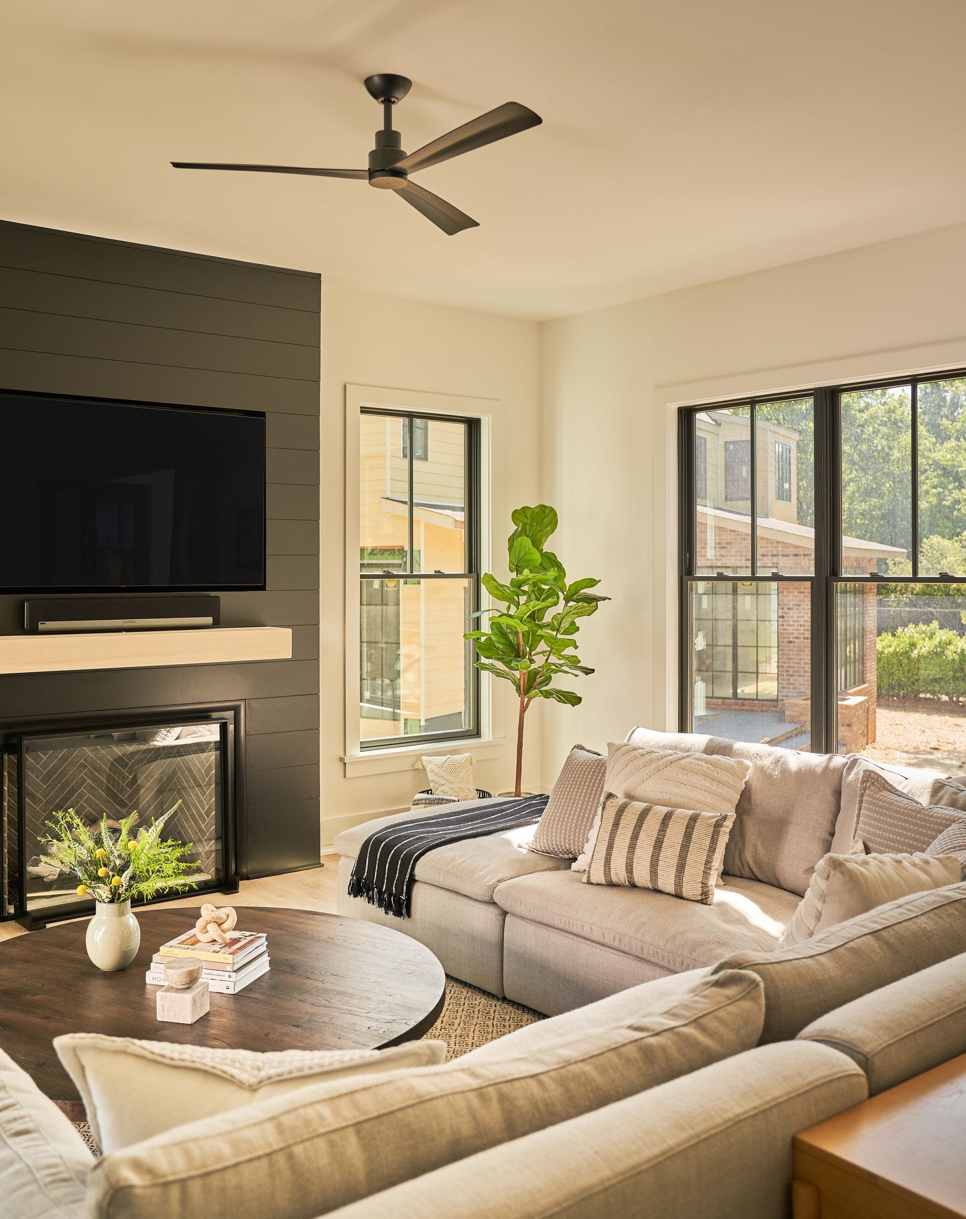 A living room with a couch , fireplace , television and ceiling fan.