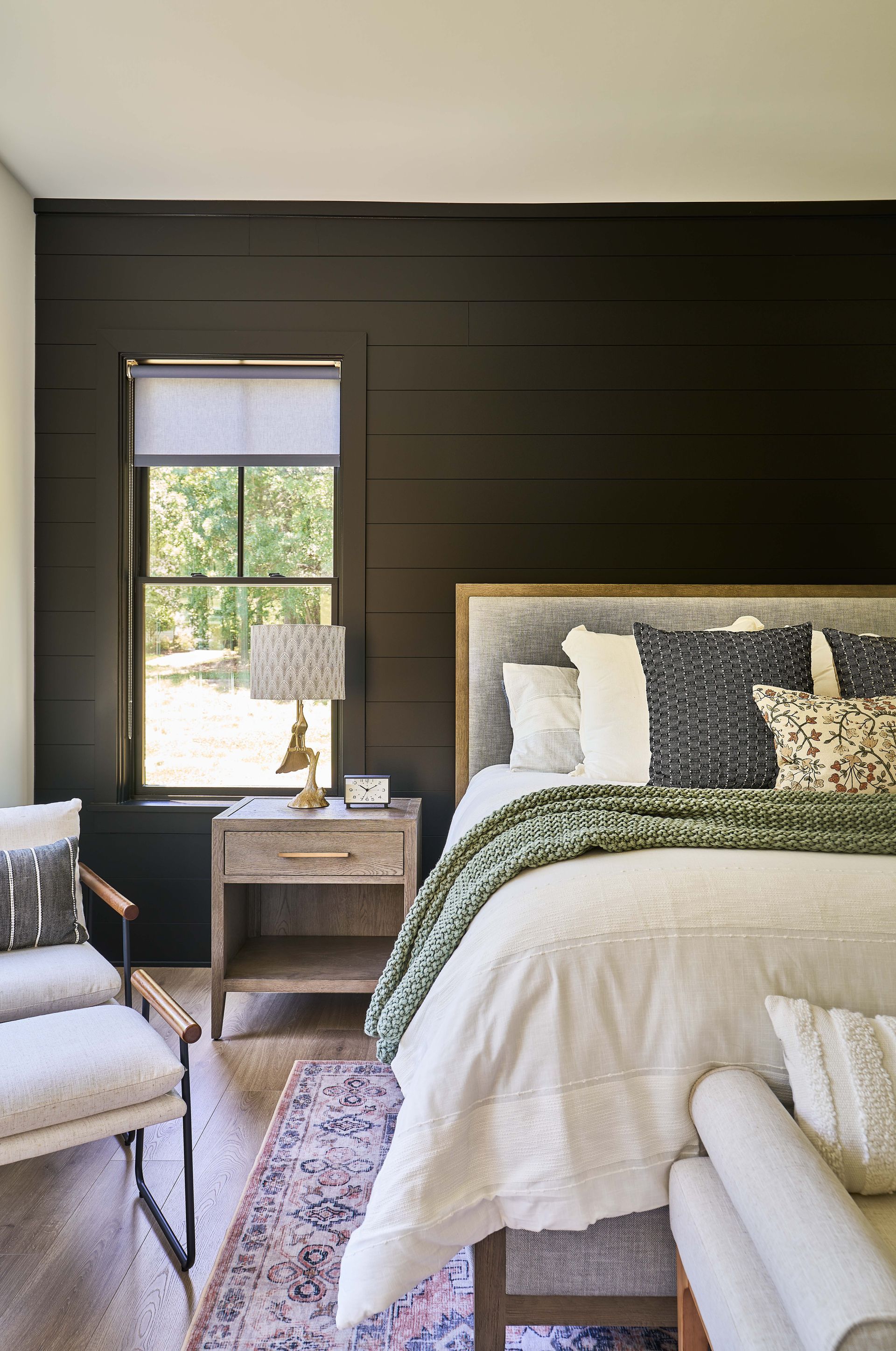 A bedroom with a bed , nightstand , chair and window.