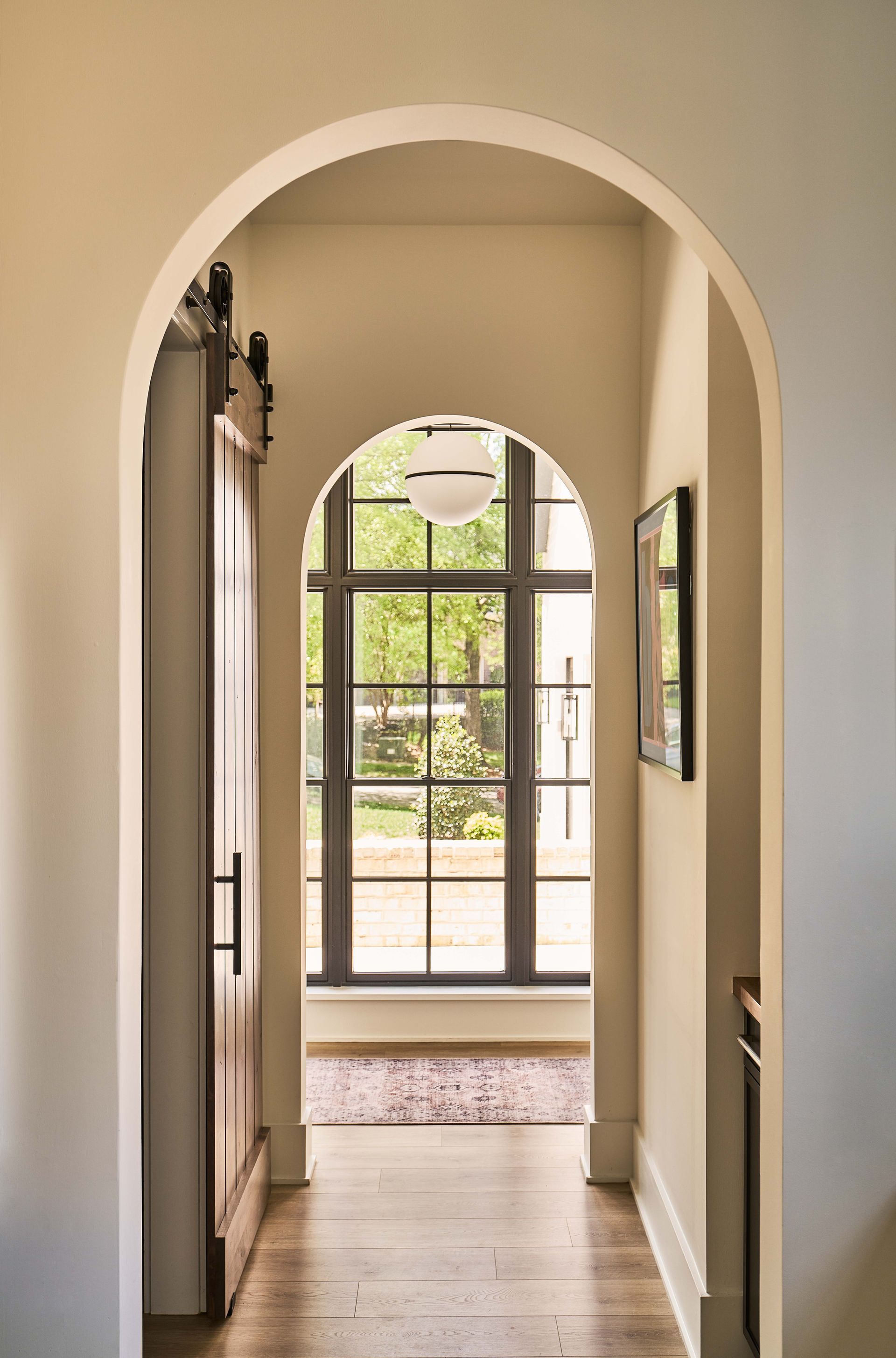 A hallway with an archway and a large window.