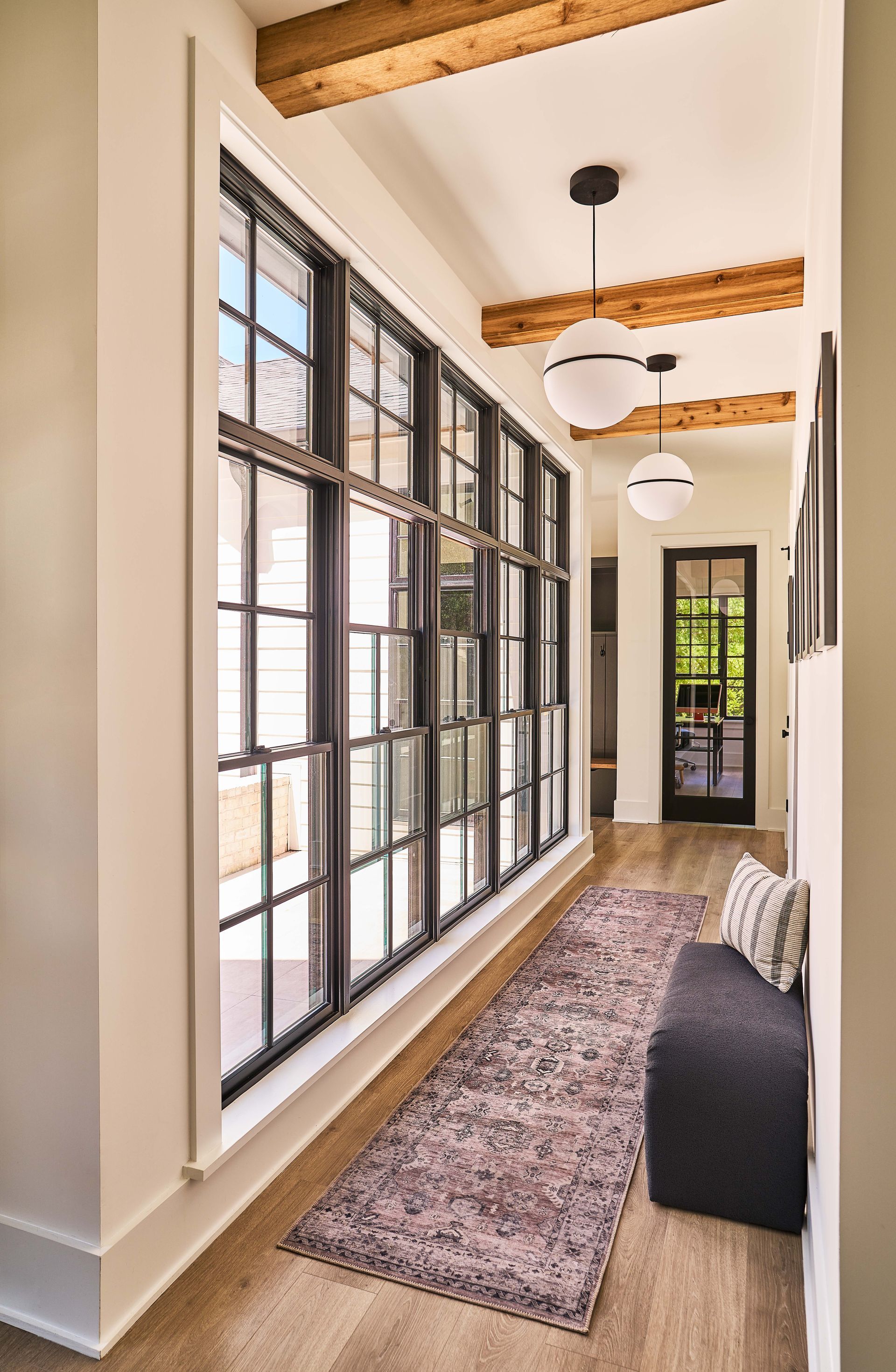 A hallway with a lot of windows and a rug.