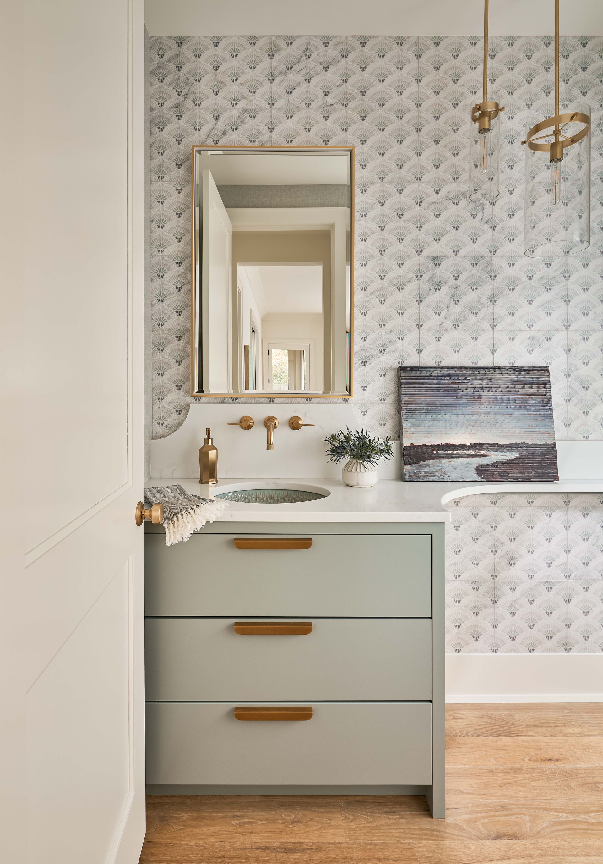 A bathroom with a sink , mirror and drawers.