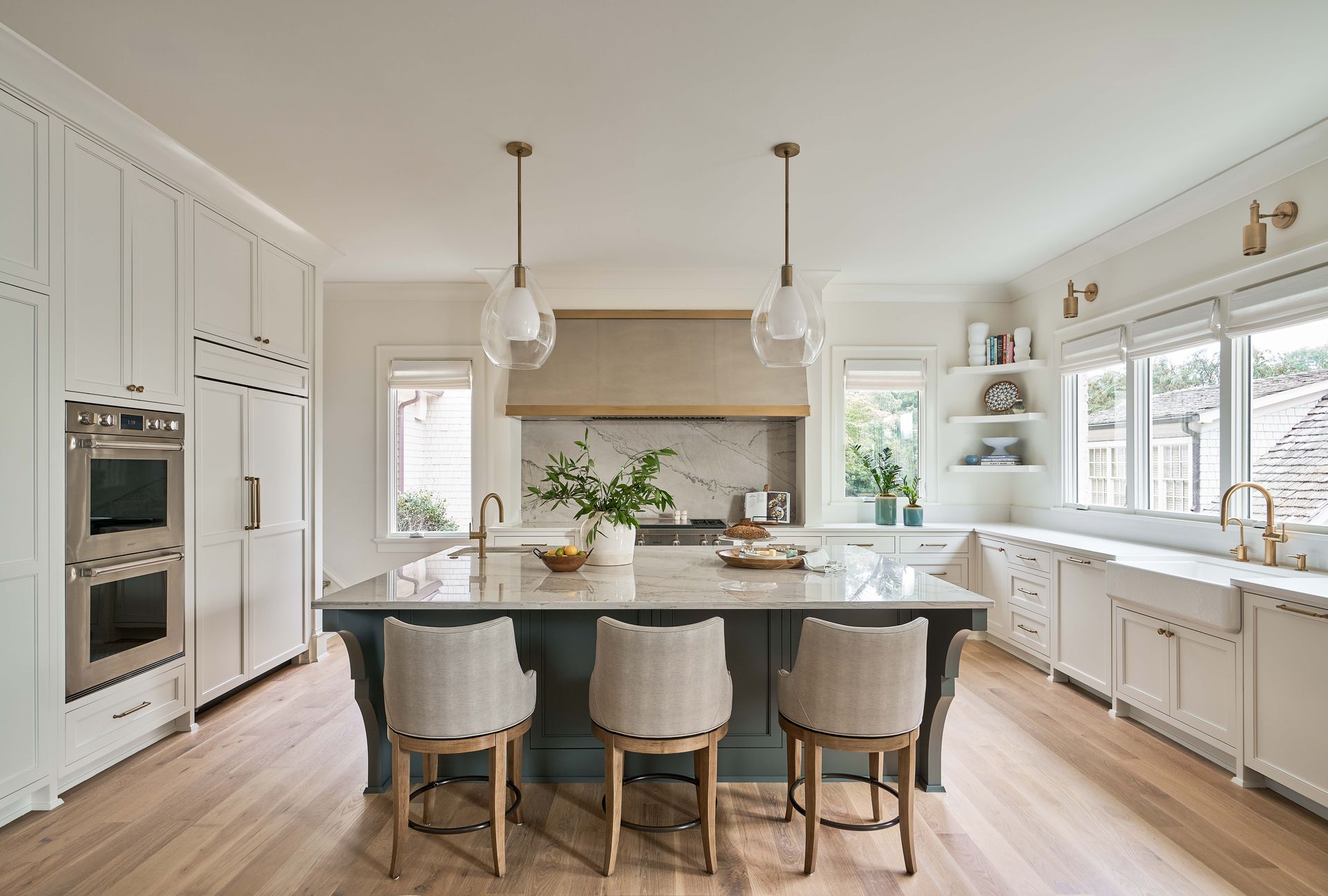 A kitchen with white cabinets , stainless steel appliances , a large island , and a sink.