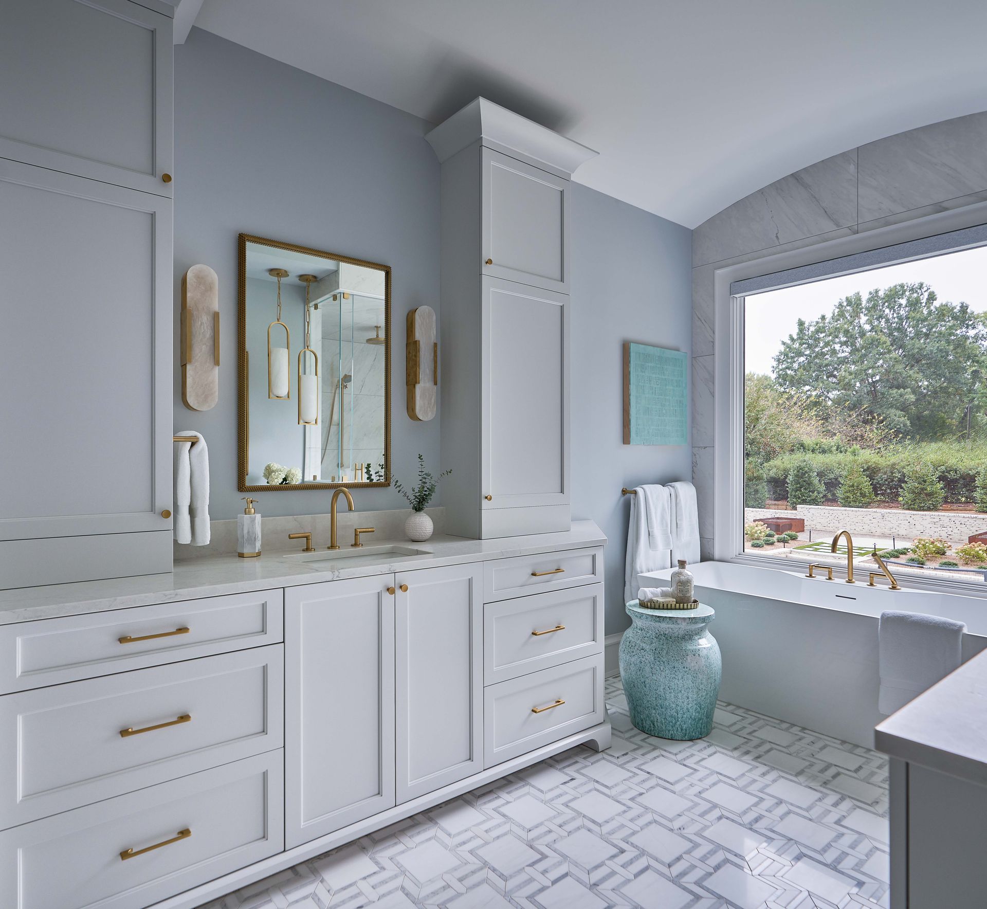 A bathroom with white cabinets and a large window