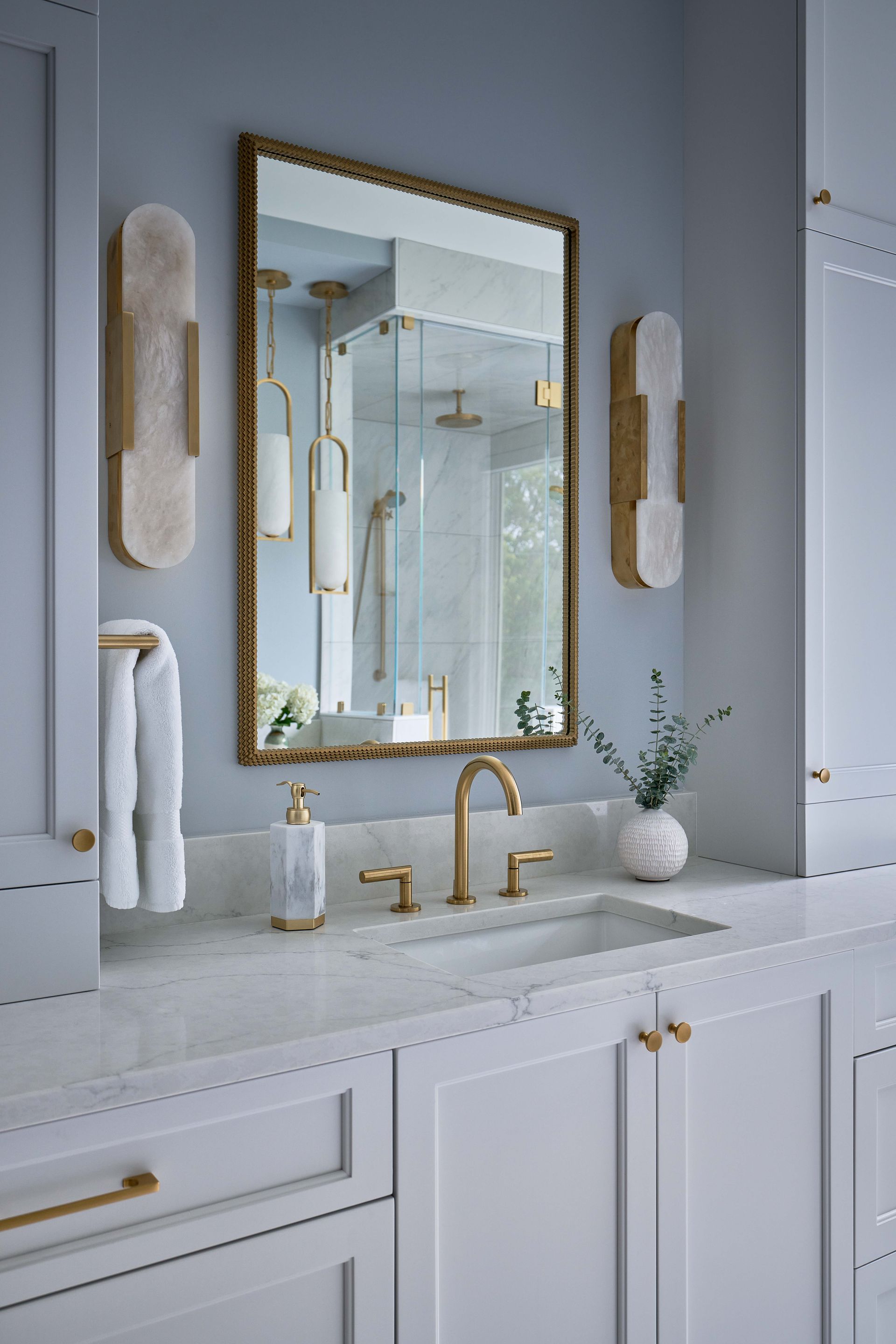 A bathroom with a sink , mirror , and cabinets.