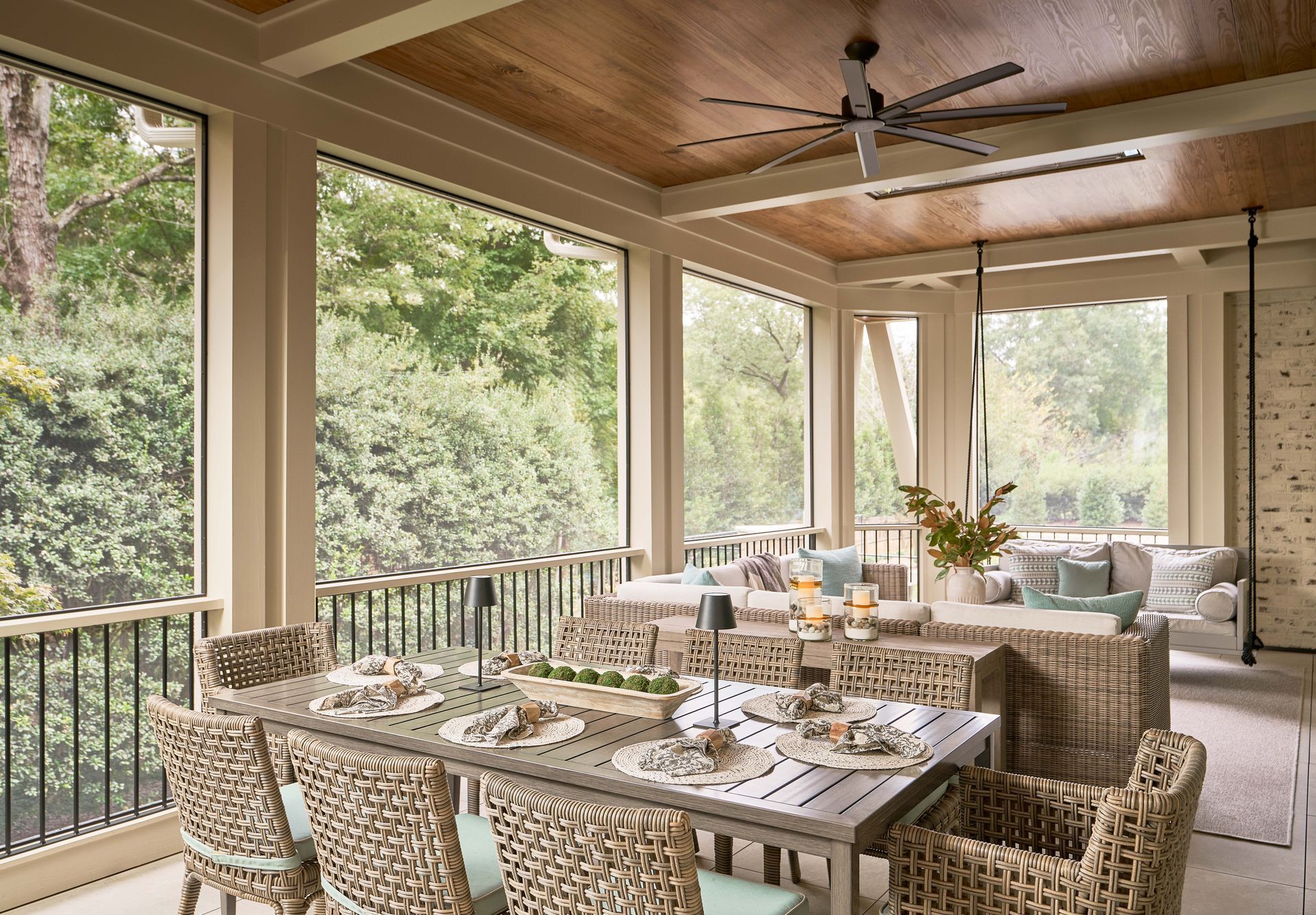 A screened in porch with a table and chairs and a ceiling fan.