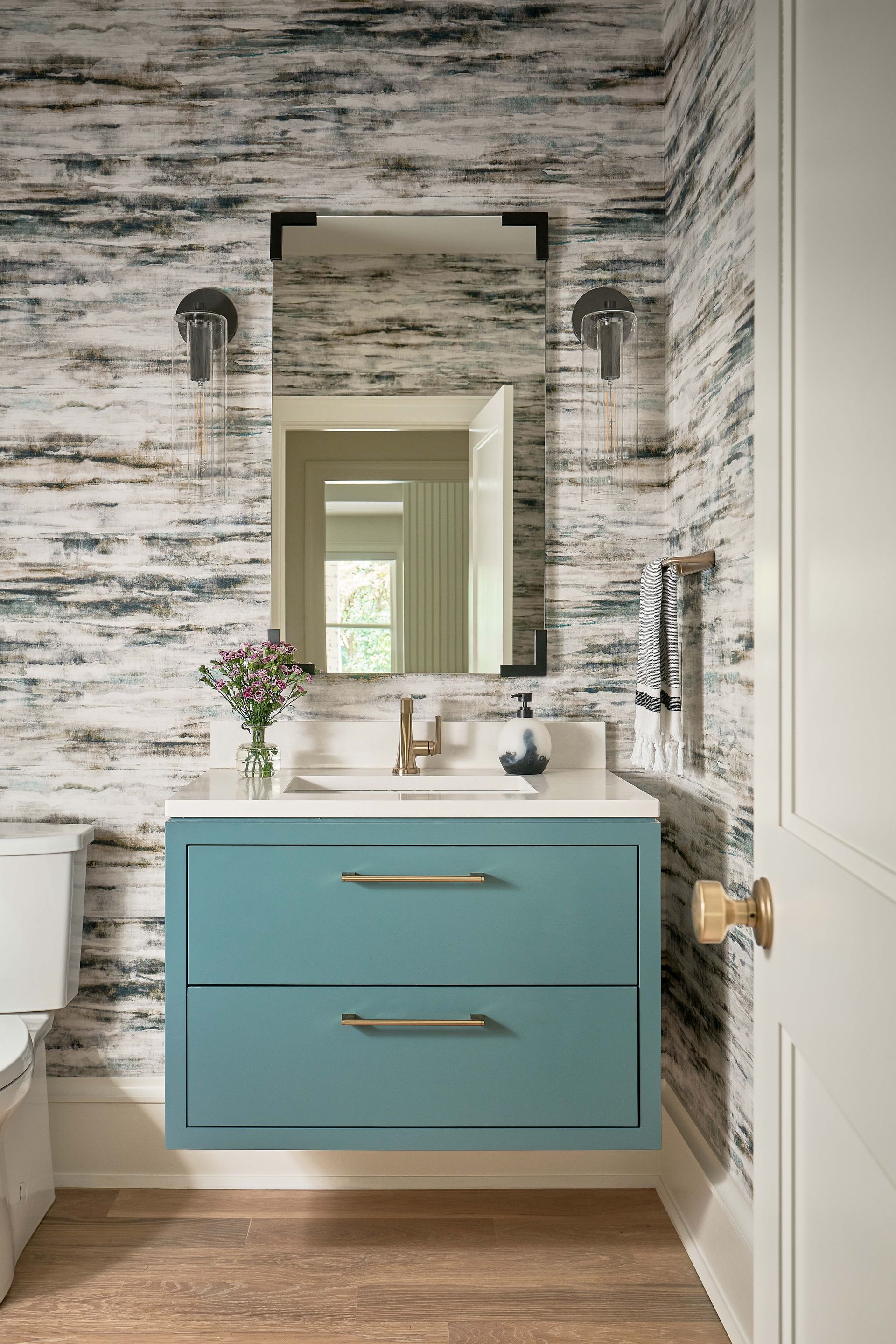 A bathroom with a blue vanity and a mirror.