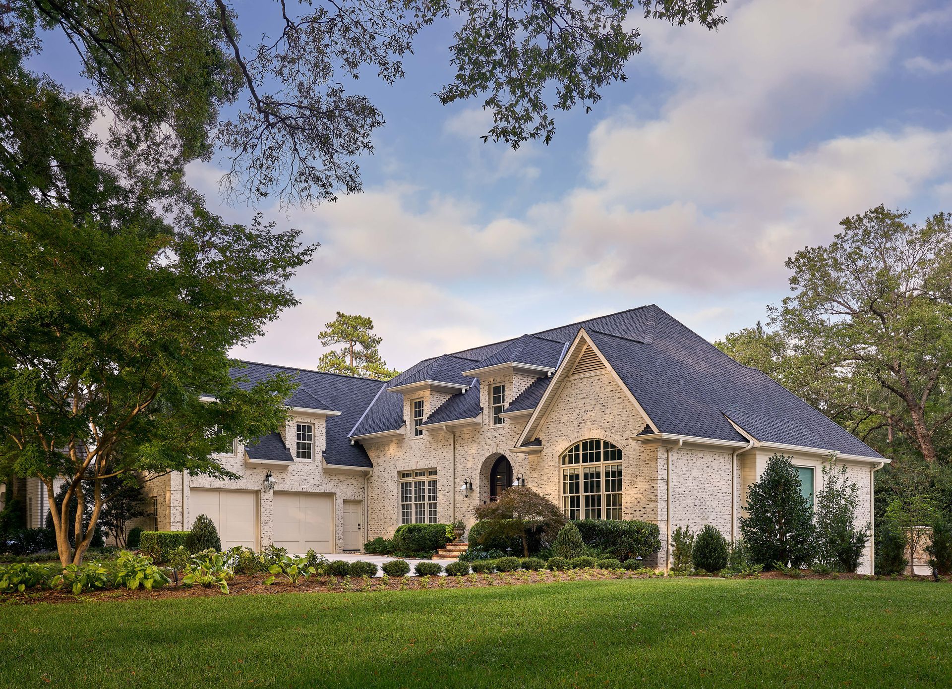 A large house with a blue roof is surrounded by trees