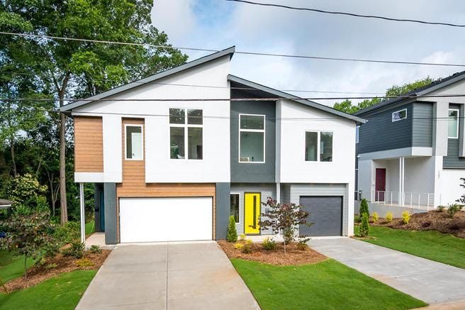 a white and gray house with a yellow door and a garage .