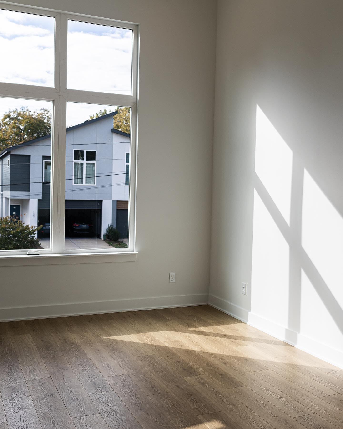 an empty room with hardwood floors and a large window