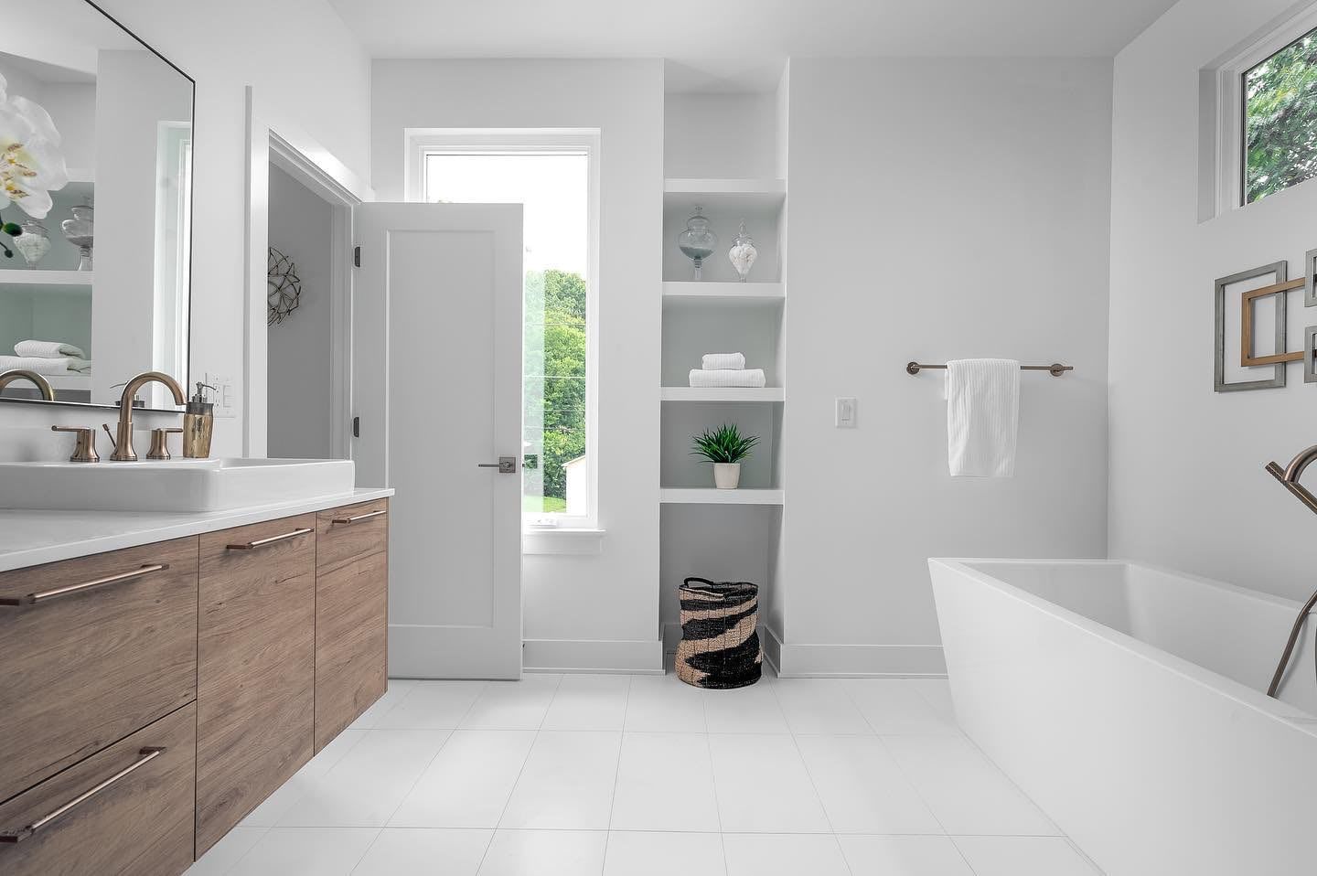 a bathroom with a tub , sink , mirror and window 