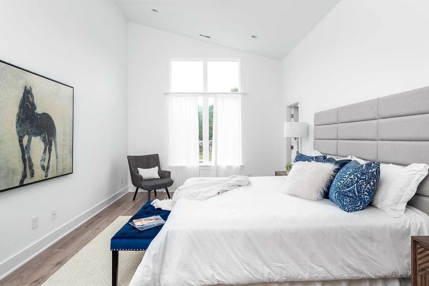 a bedroom with a large bed , chair and painting on the wall .