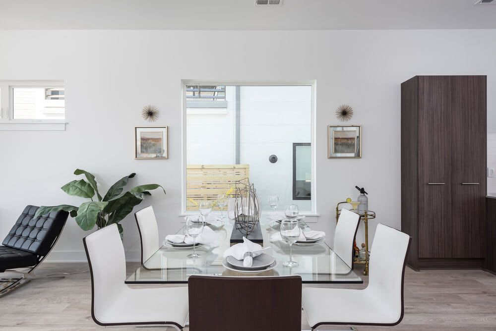 A dining room with a glass table and white chairs.