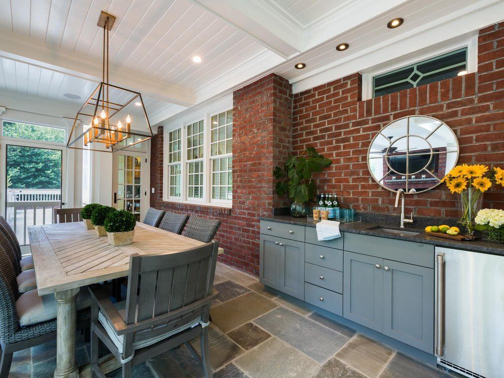 A dining room with a table and chairs and a brick wall.