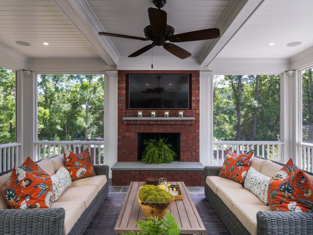 A screened in porch with a fireplace and a flat screen tv.