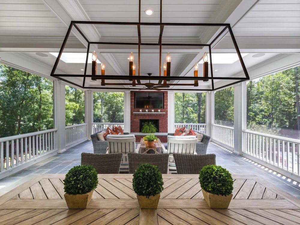 A porch with a table and chairs and a chandelier hanging from the ceiling.