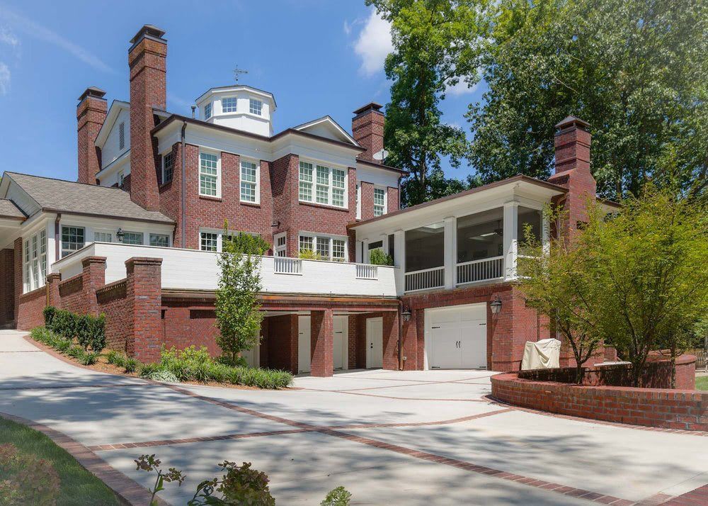 a large brick house with two garages and a large driveway .