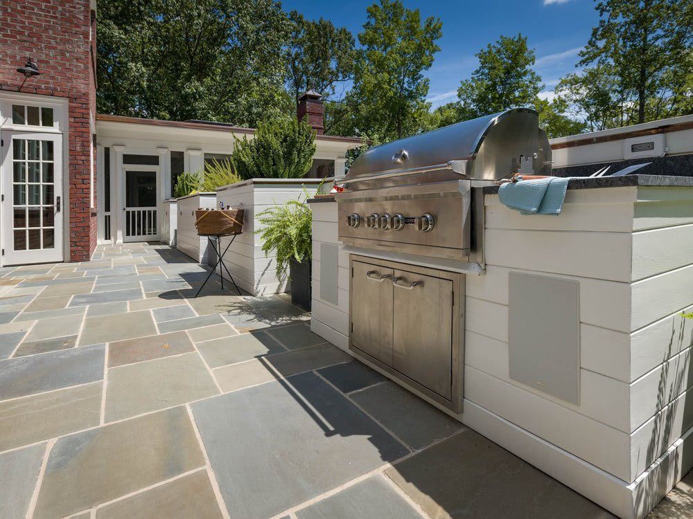 A stainless steel grill is sitting on a patio next to a brick building.
