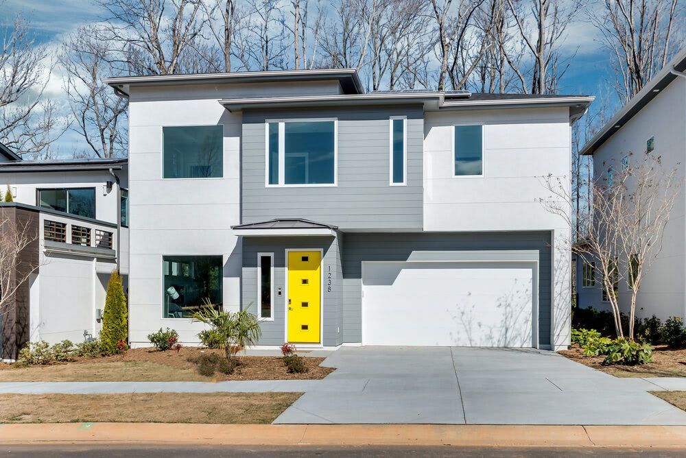 a white and gray house with a yellow door and garage .