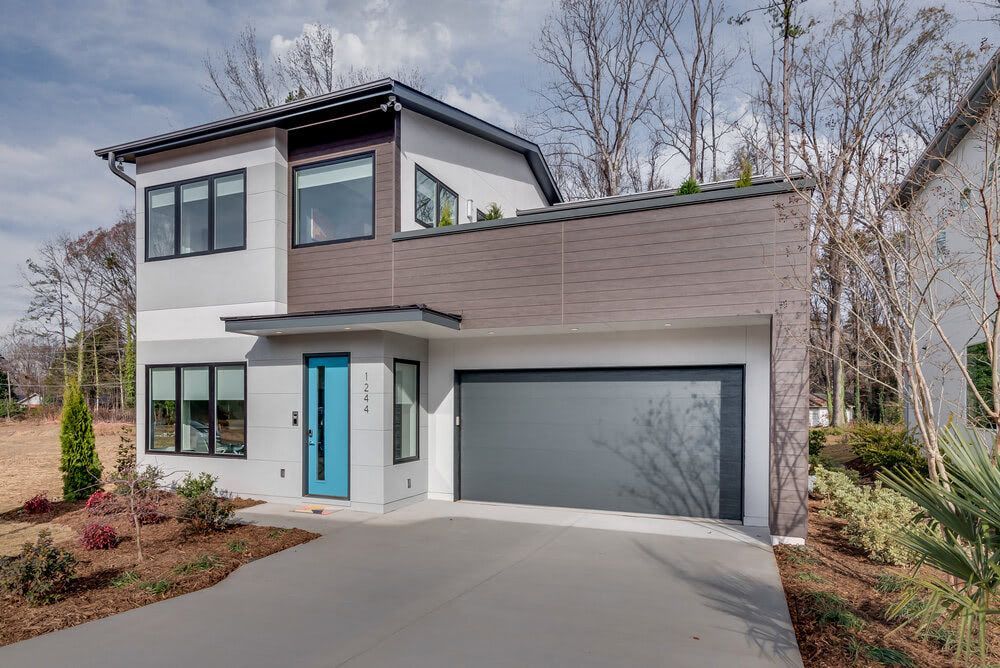 A modern house with a blue door and a gray garage door.