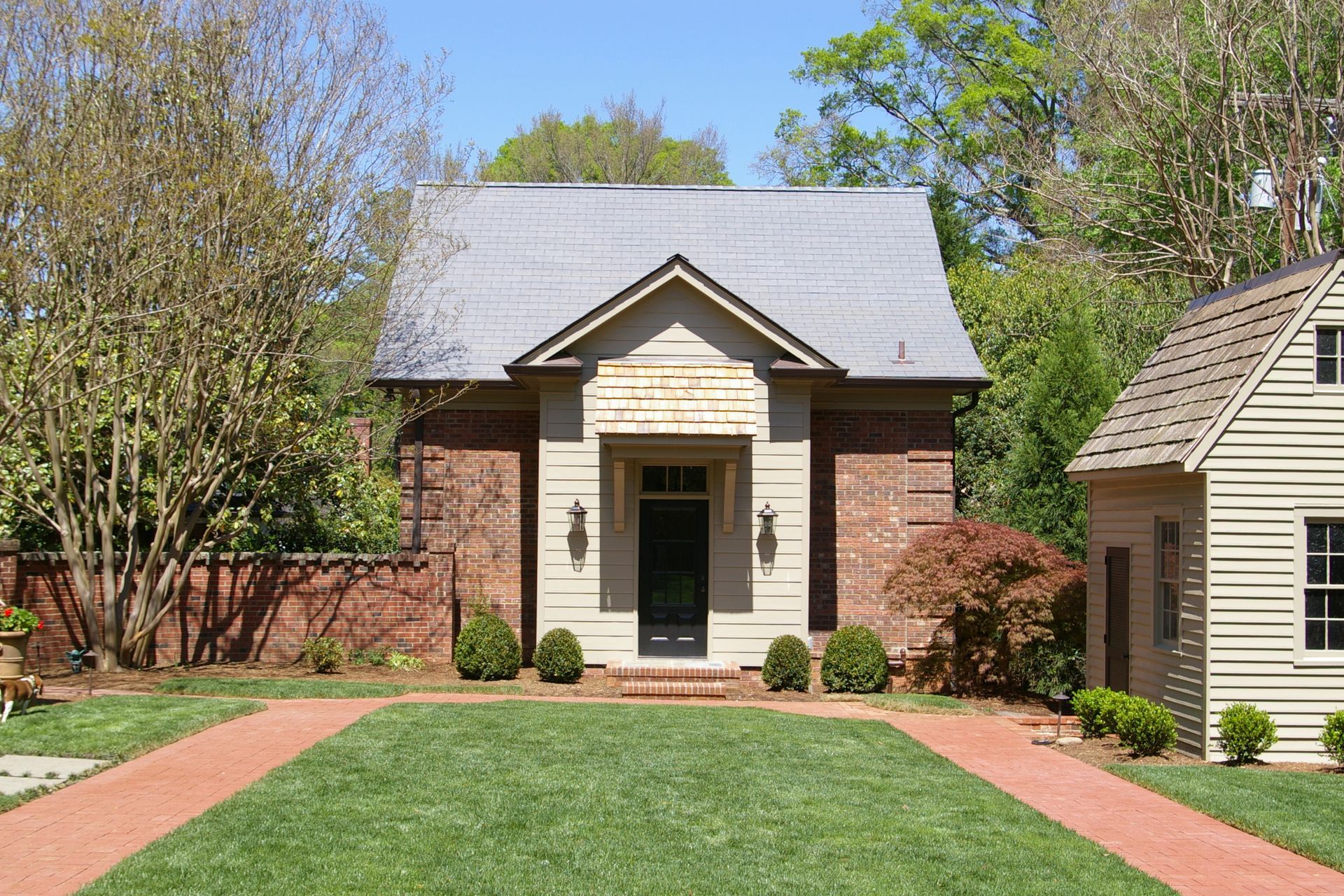 A small brick house with a large lawn in front of it