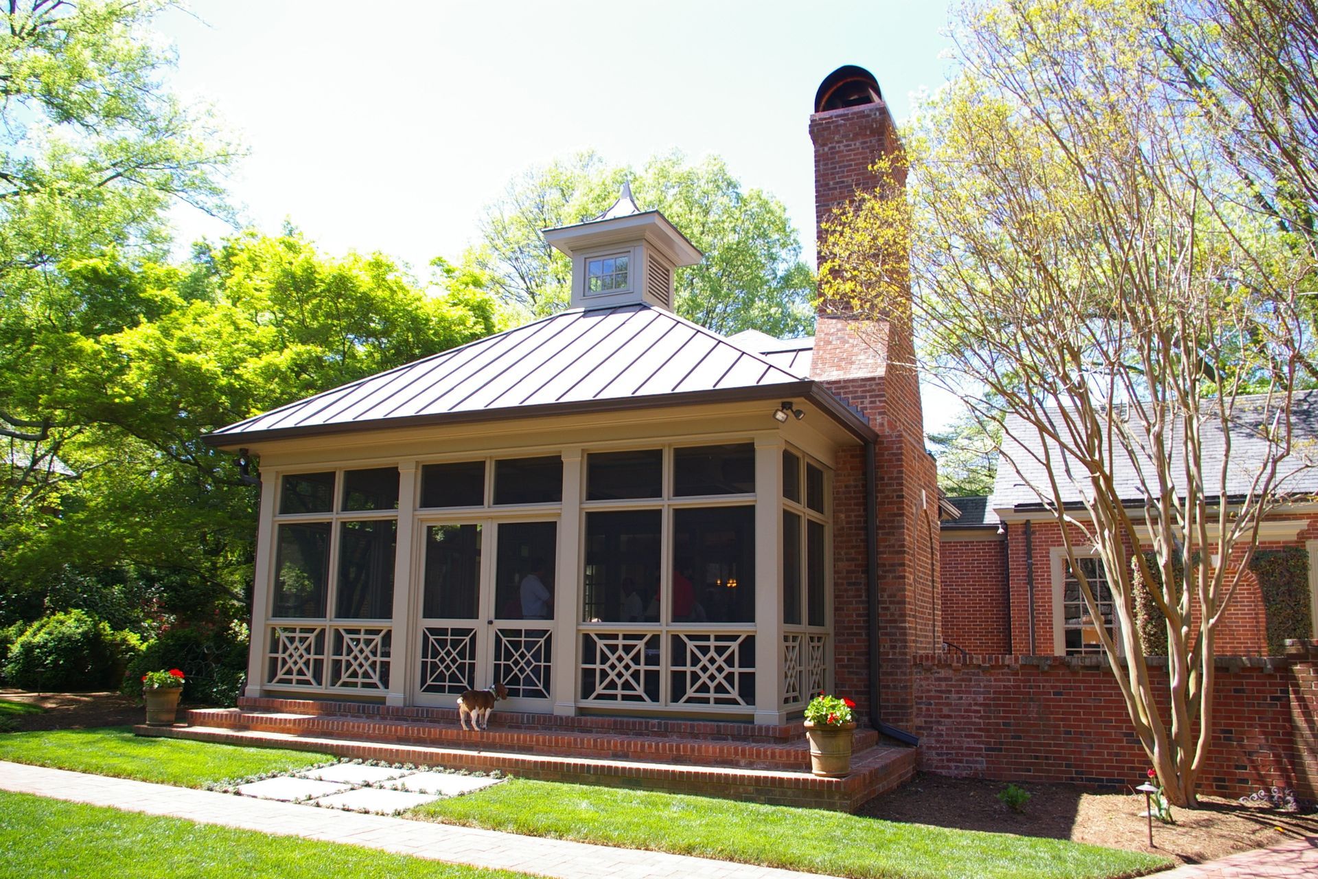 A brick house with a screened in porch and a chimney