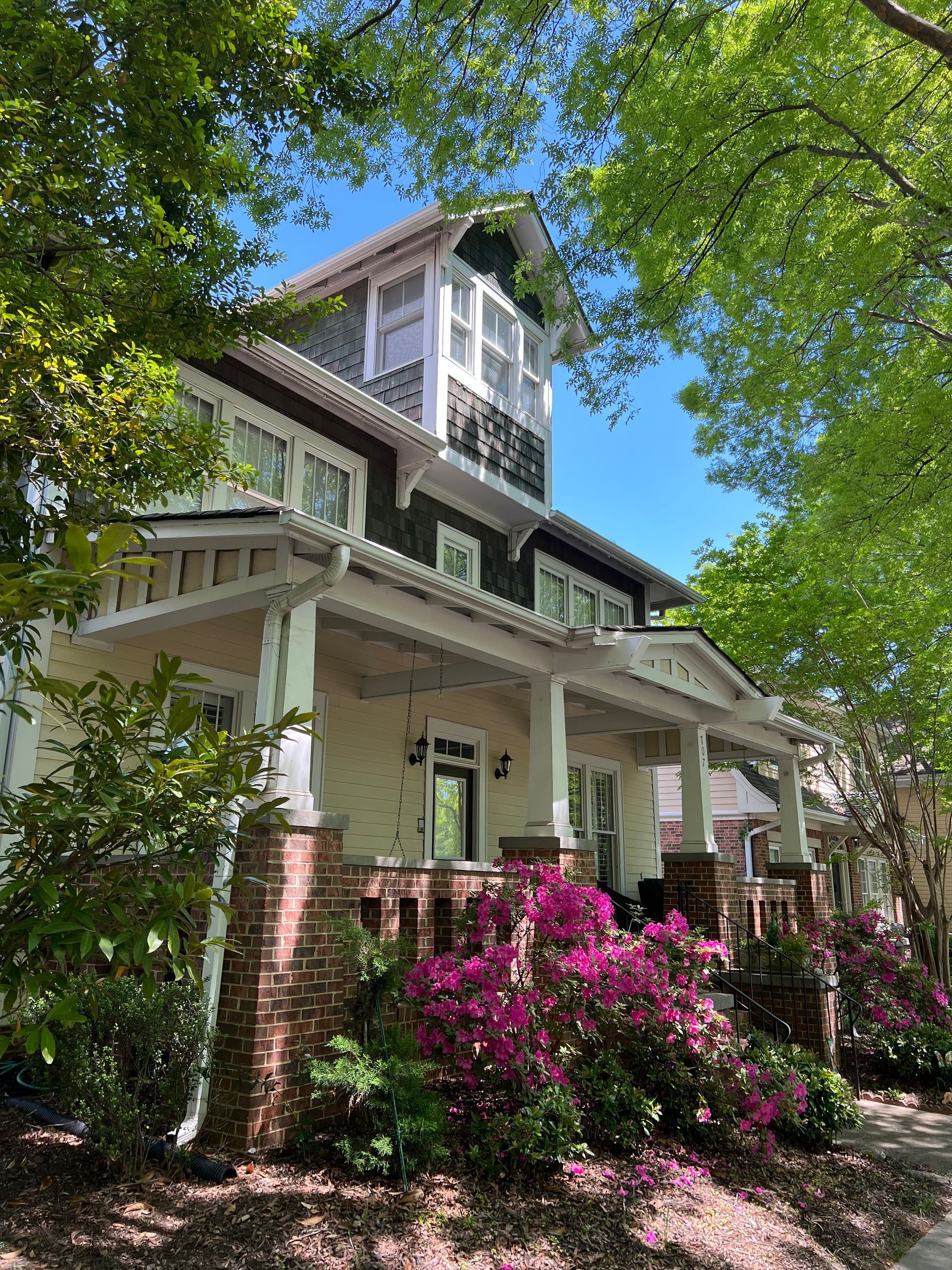 A large house with a porch and flowers in front of it.
