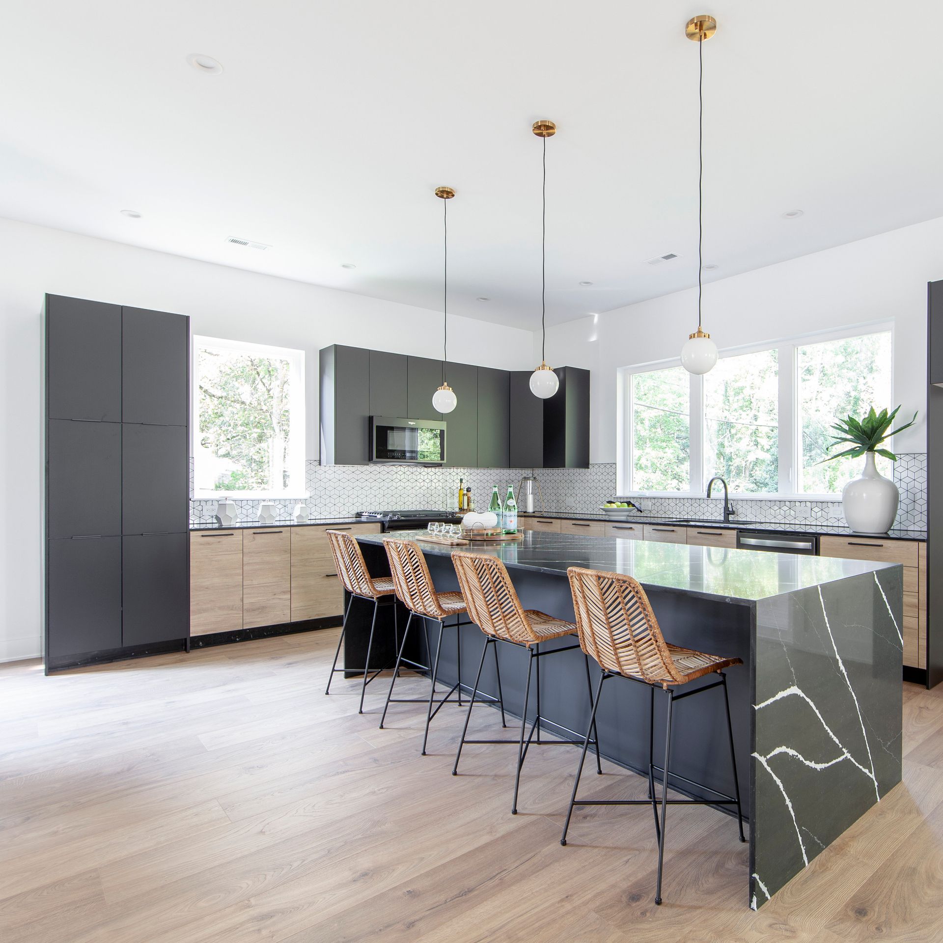 A kitchen with a large island and wicker chairs