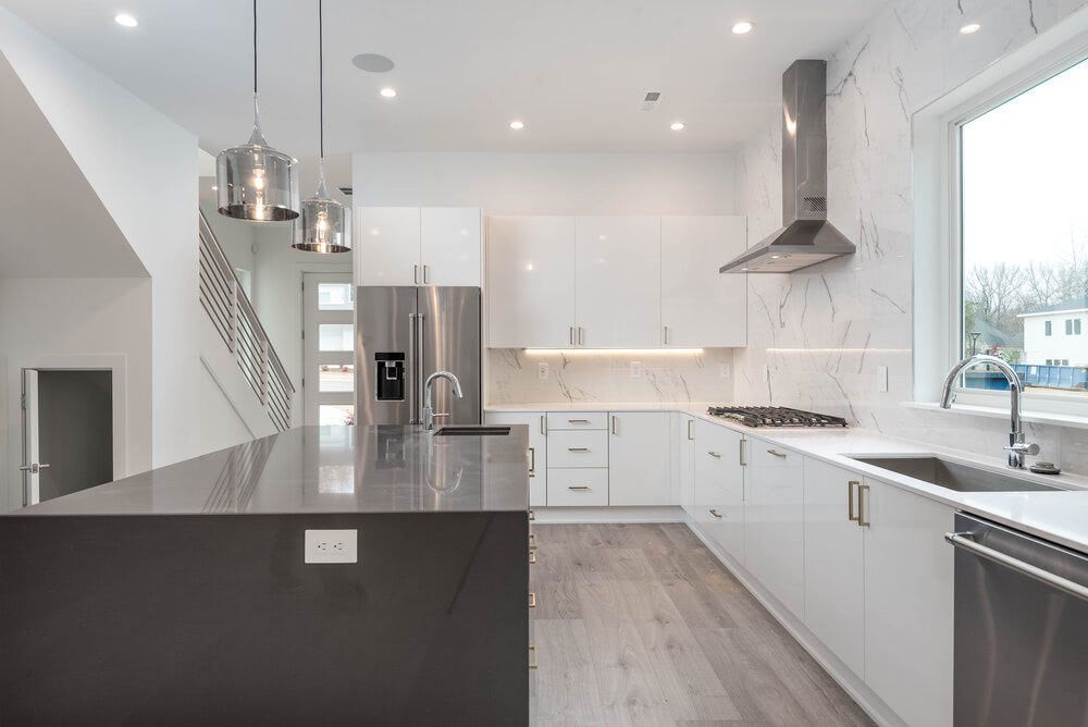A kitchen with white cabinets , stainless steel appliances , a sink and a refrigerator.