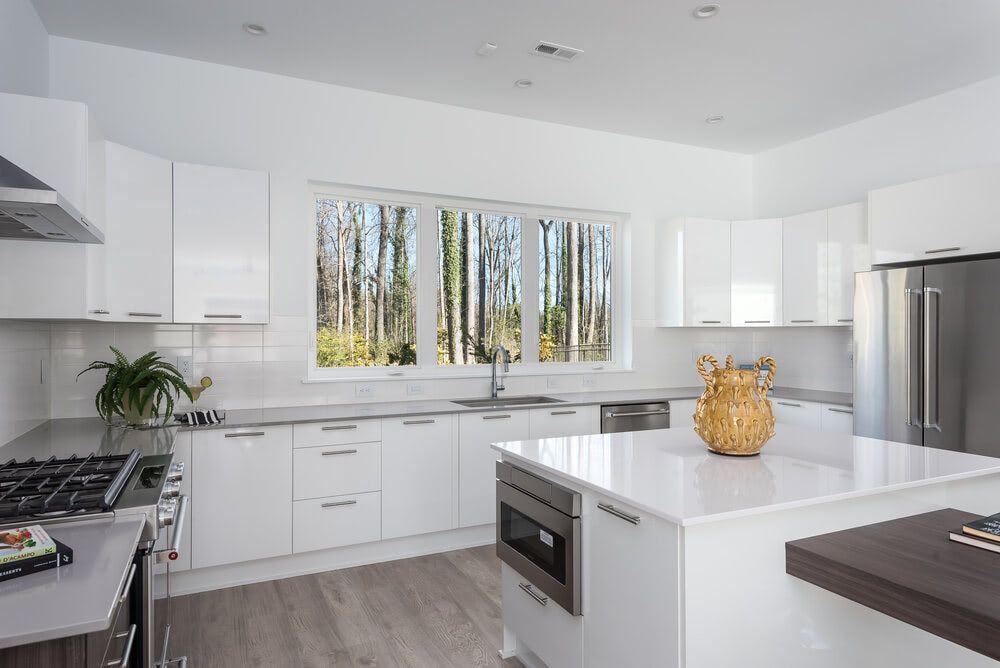 A kitchen with white cabinets , stainless steel appliances , and a large island.
