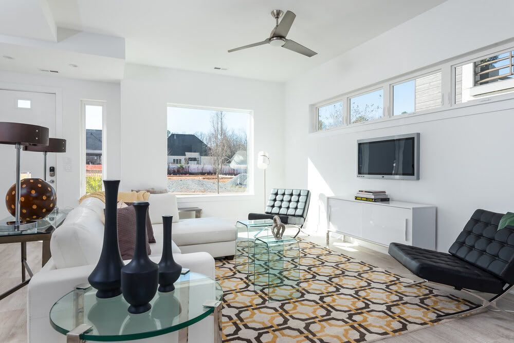 A living room with a ceiling fan and a flat screen tv.