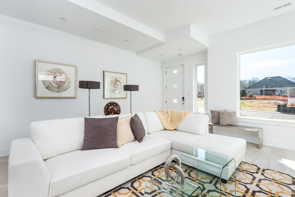 A living room with a white couch and a glass coffee table.