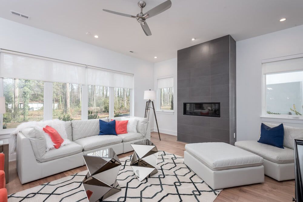 A living room with white furniture , a fireplace and a ceiling fan.