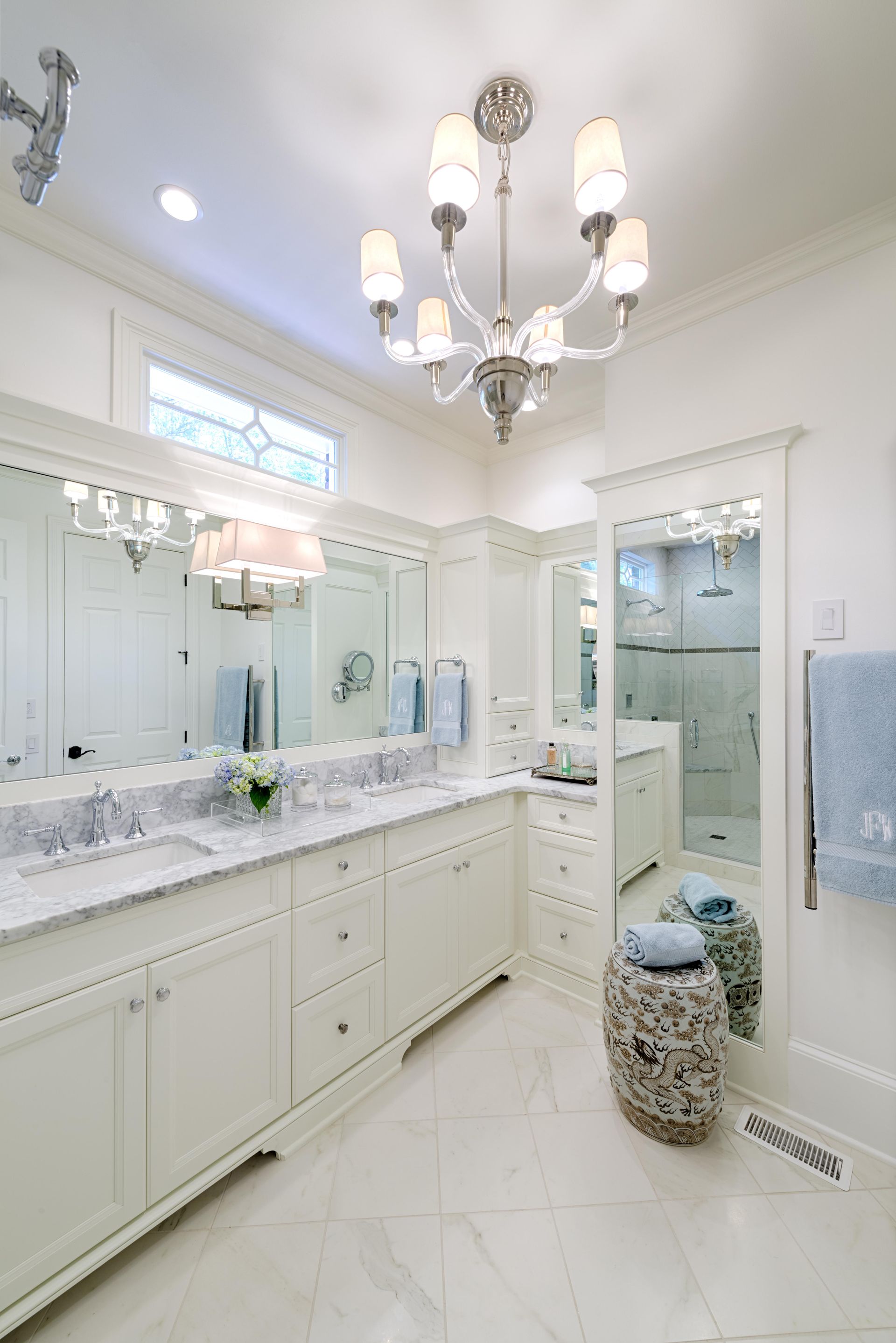 A bathroom with two sinks , a mirror and a chandelier.