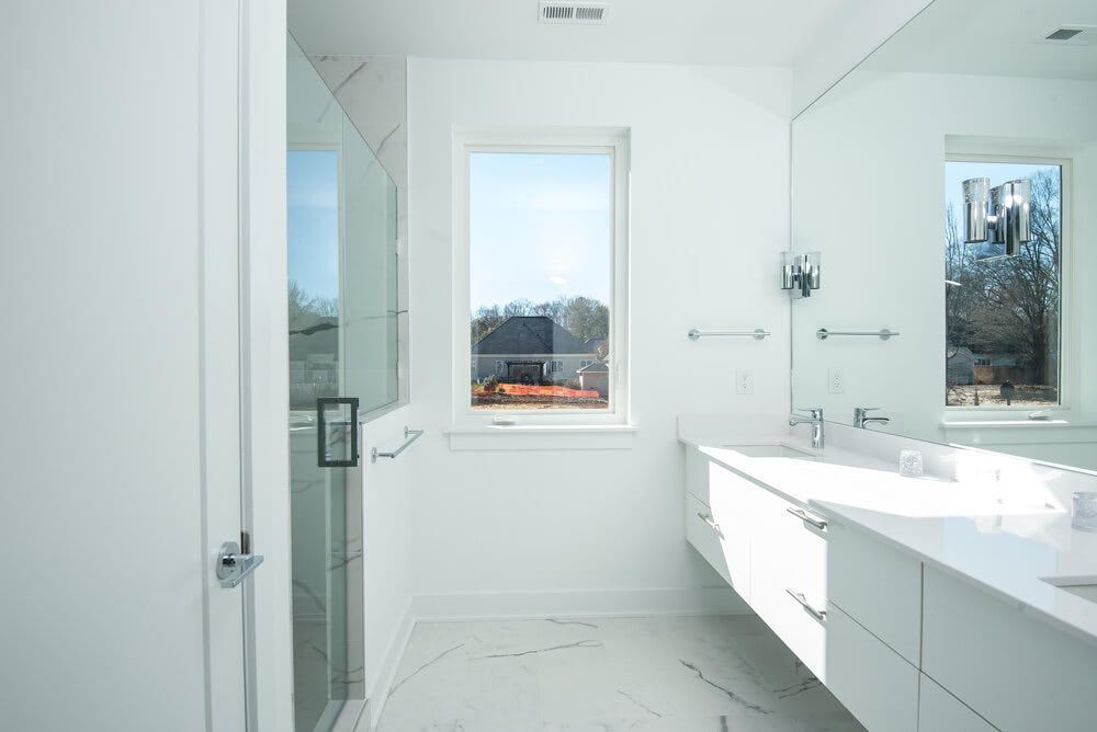 A bathroom with a sink , mirror and window.