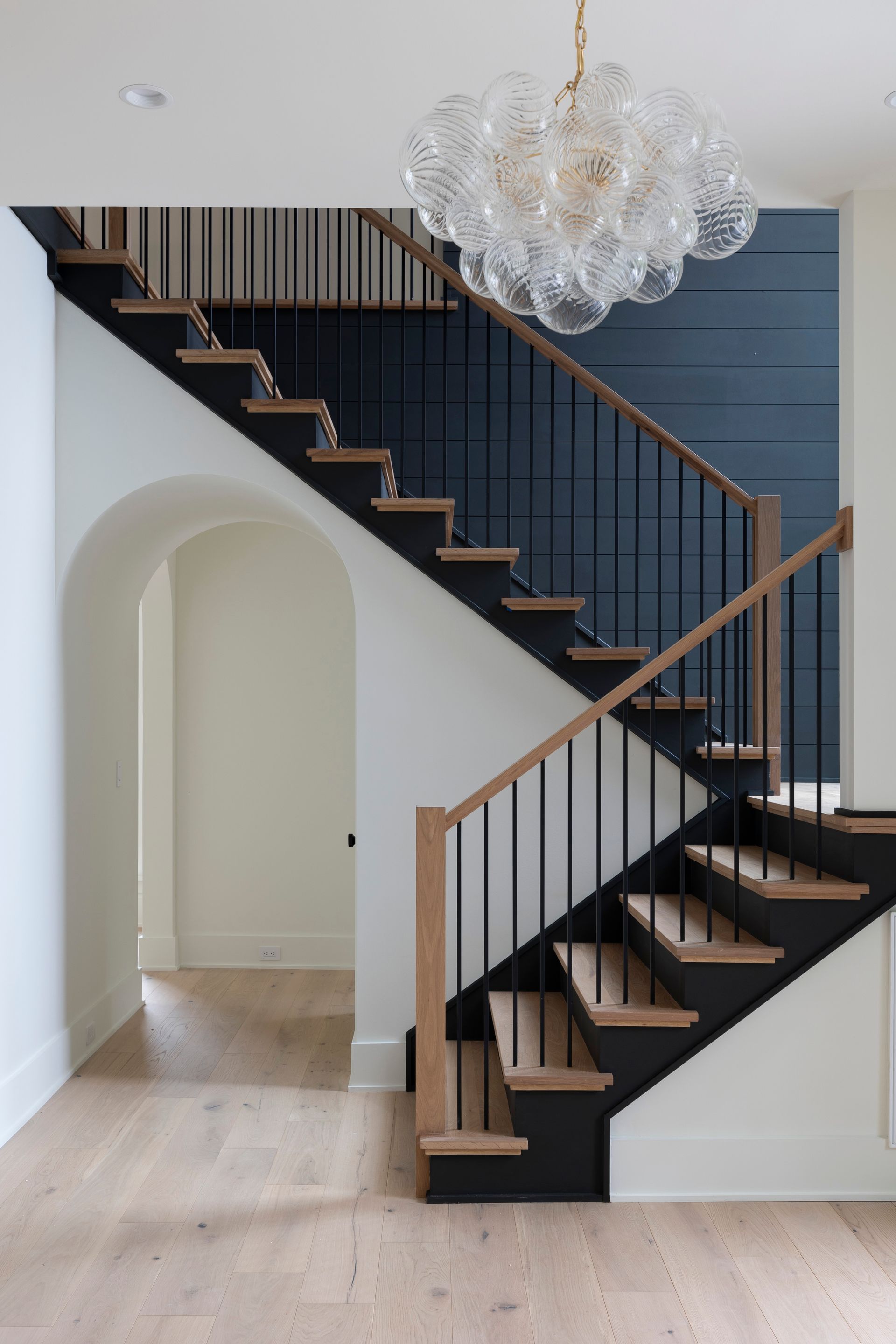 A staircase in a house with a chandelier hanging from the ceiling.