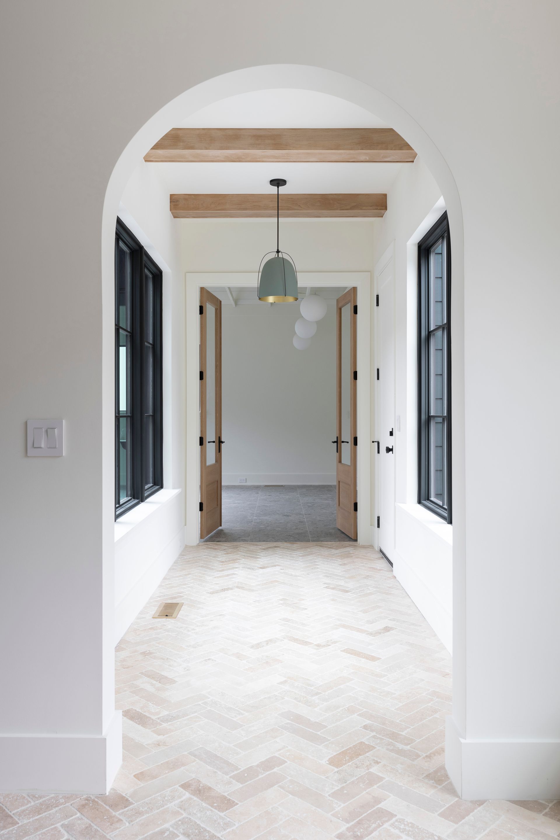 A hallway with a wooden archway and a herringbone floor.