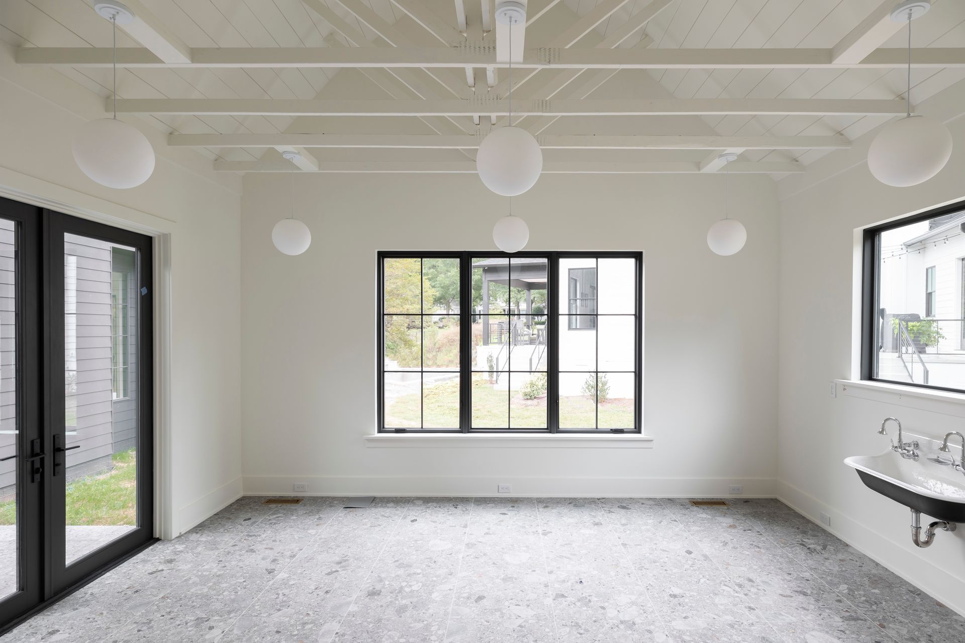A large empty room with a sink and a lot of windows.