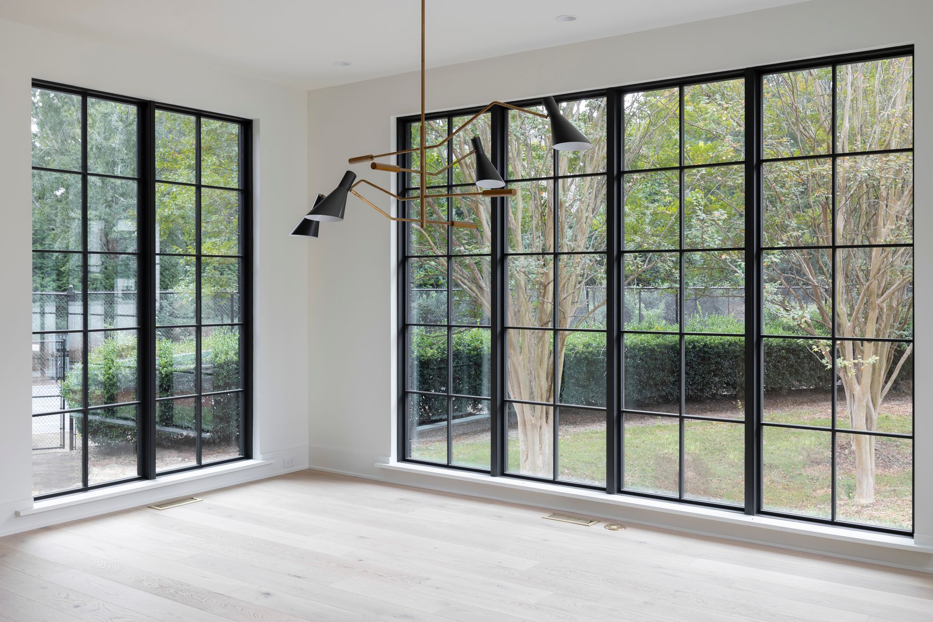 An empty room with lots of windows and a chandelier.