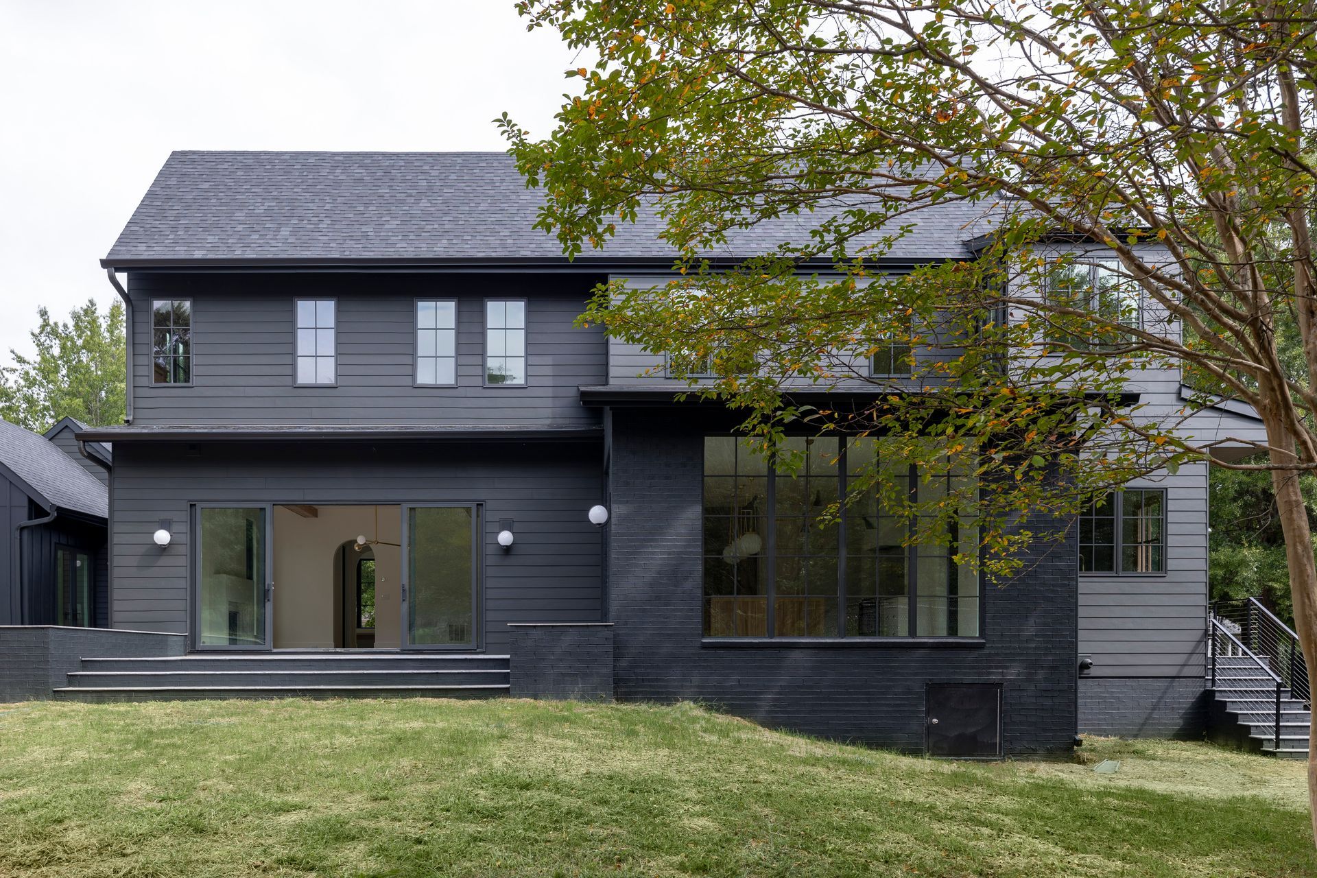 A black house with a slate roof is sitting on top of a lush green hill.