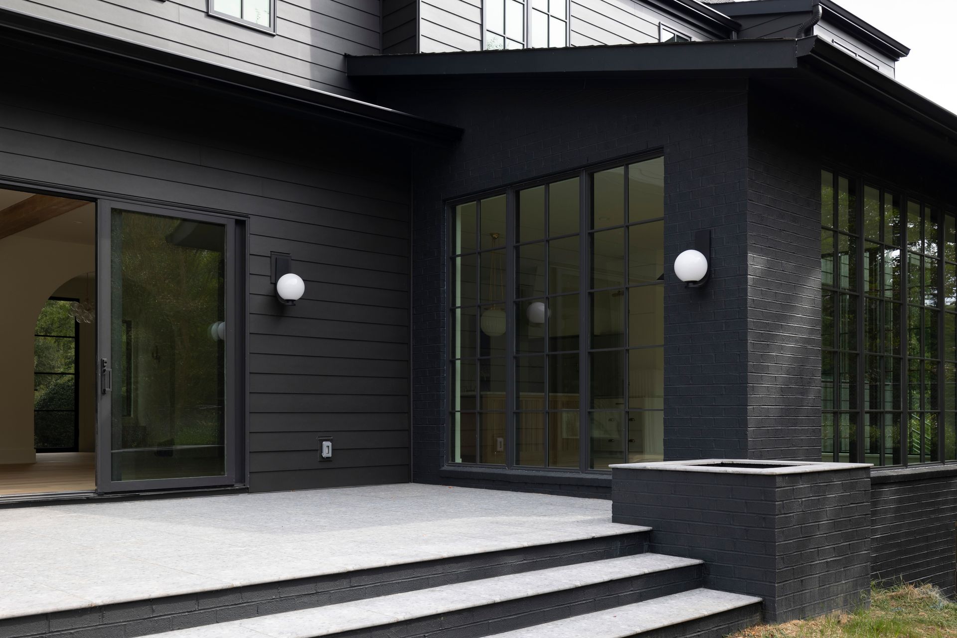 A black house with a patio and stairs in front of it.