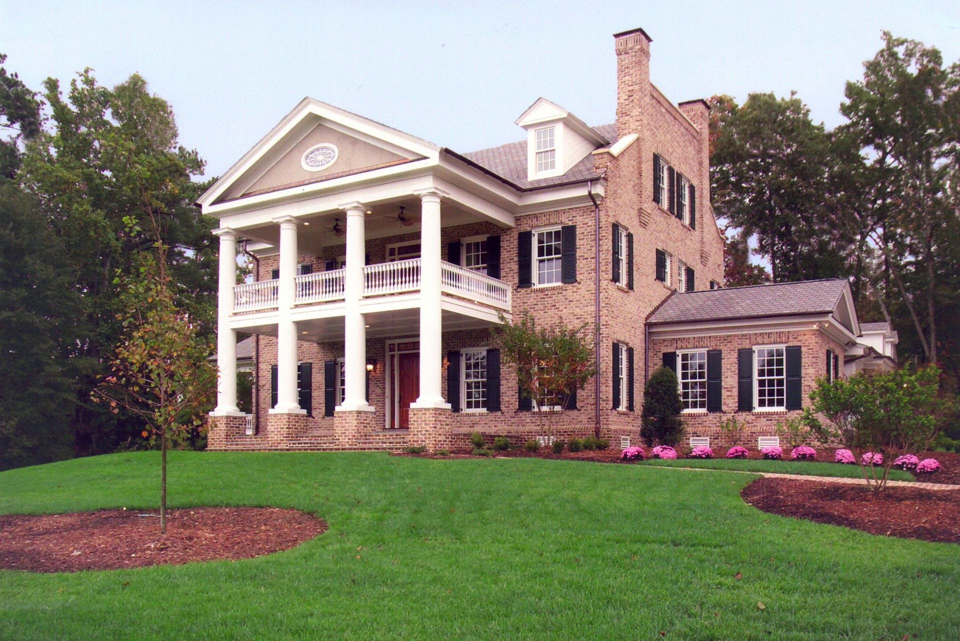 A large brick house with white columns and black shutters