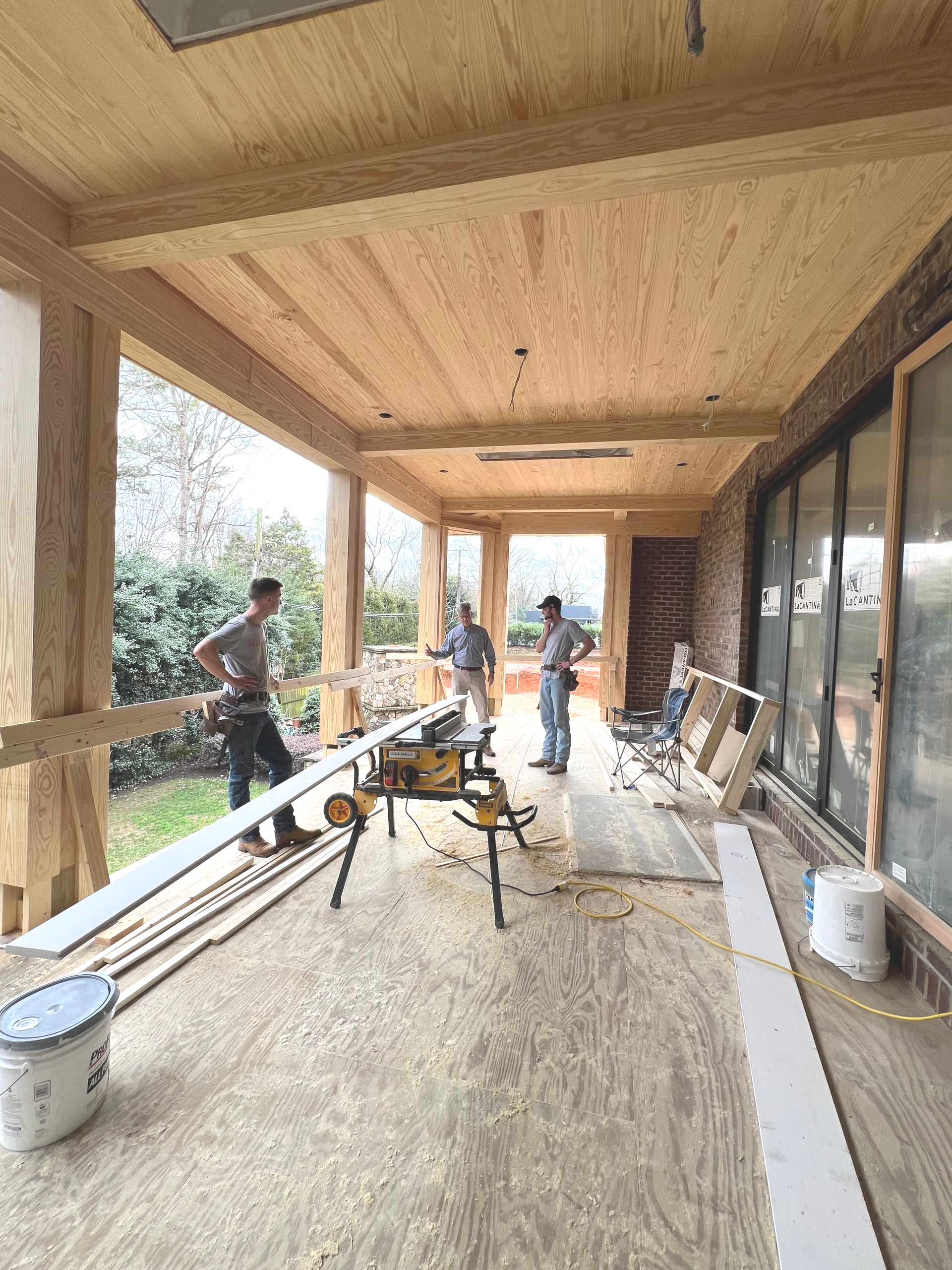 Workers installing a wood porch ceiling and siding on a covered outdoor patio