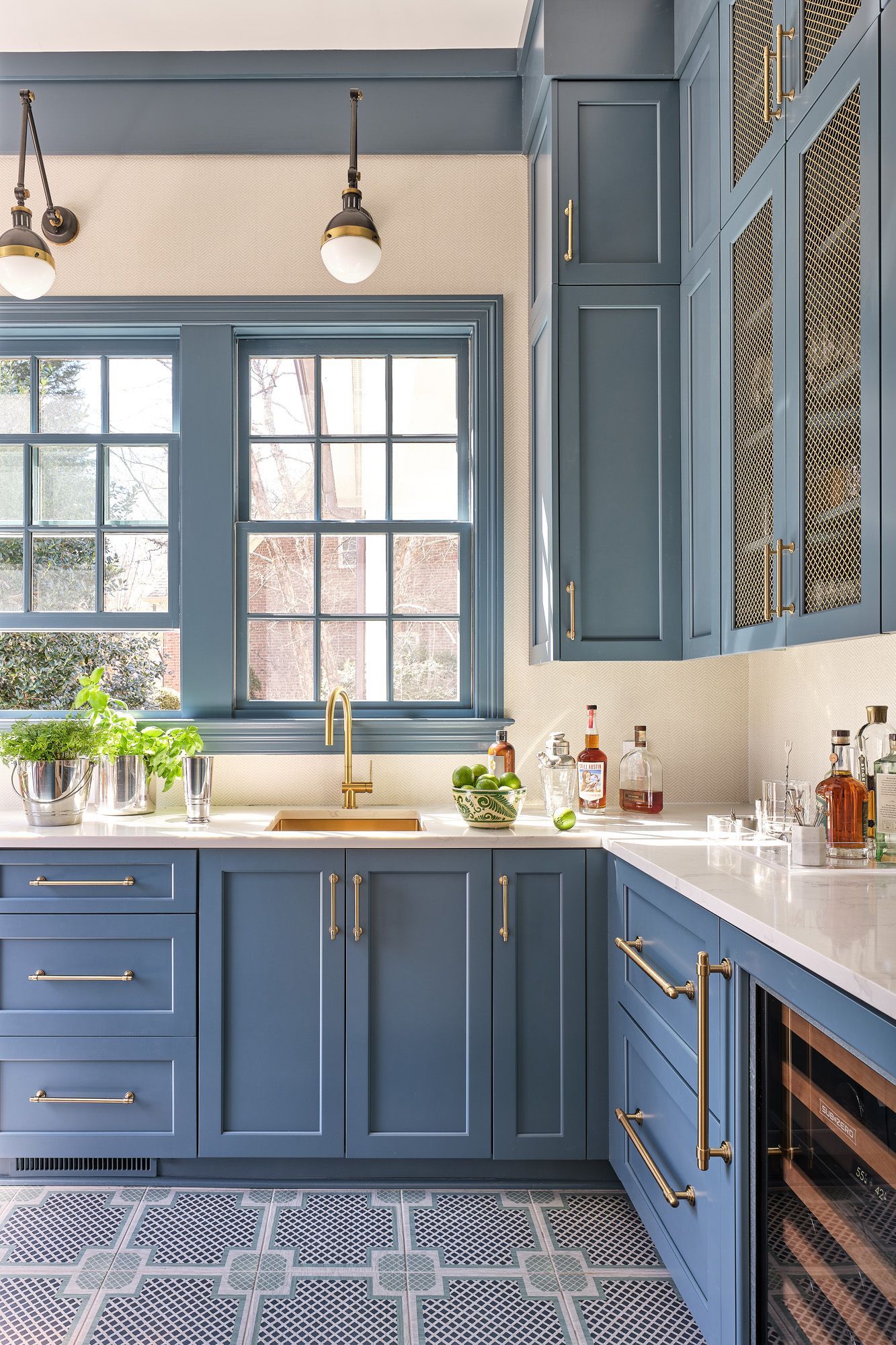 A kitchen with blue cabinets , a sink , and a window.
