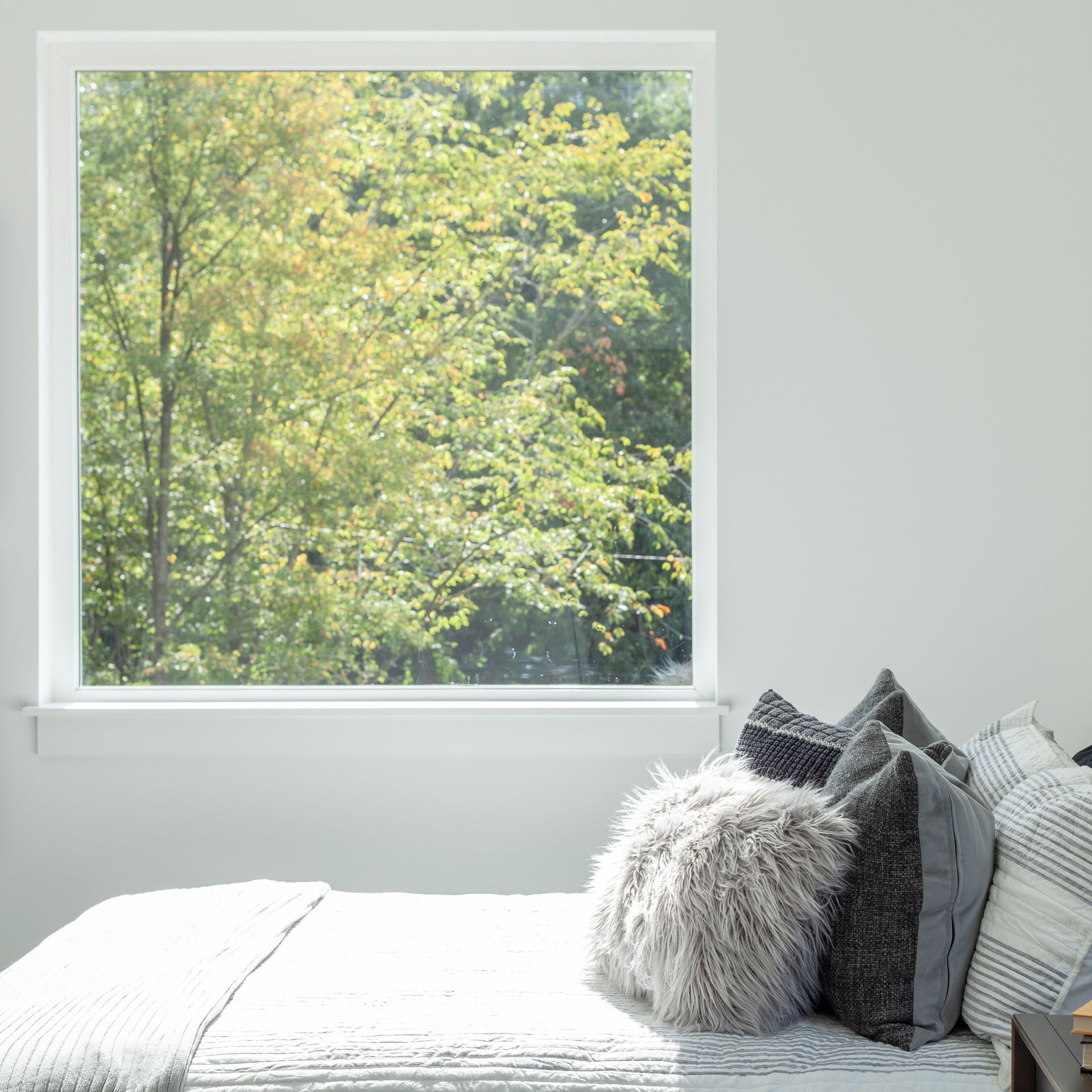 A bedroom with a bed and a window with a view of trees.