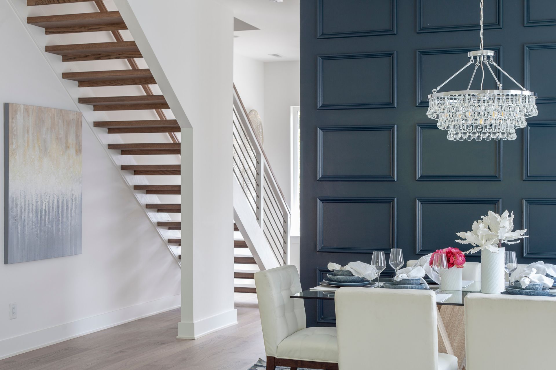 A dining room with a table and chairs and a staircase.