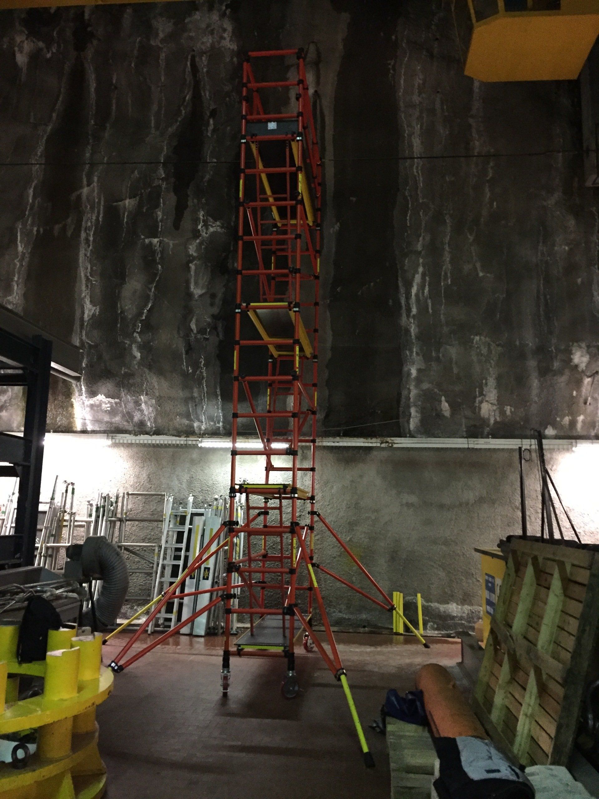 A large scaffolding is sitting in a room next to a forklift.