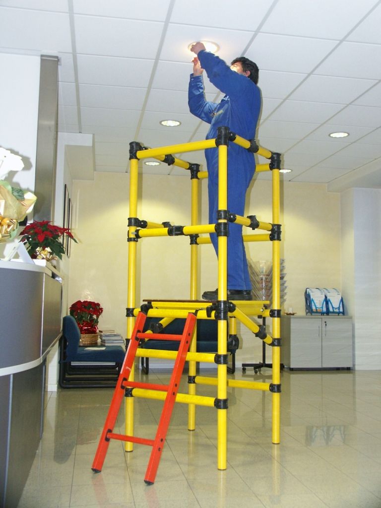 A man is standing on a yellow ladder fixing a light