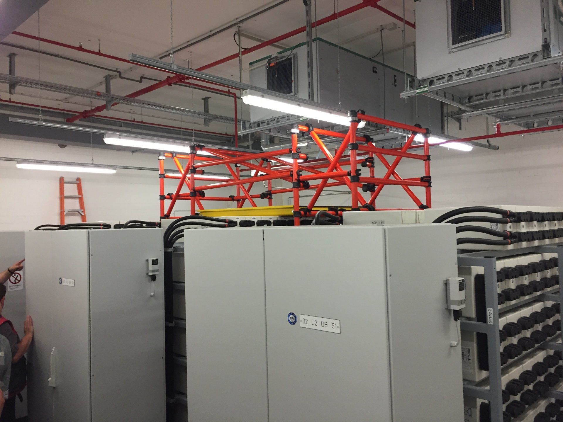 A man is standing in a room with a lot of electrical equipment.