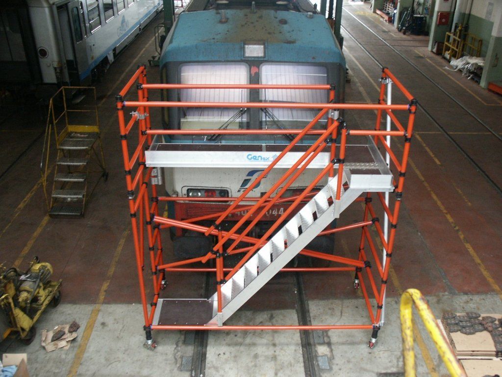 A train is sitting on a scaffolding with stairs leading up to it